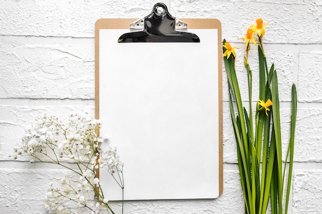 Een map voor documenten met een ijzeren wasknijper een vel papier met lentebloemen van narcissen