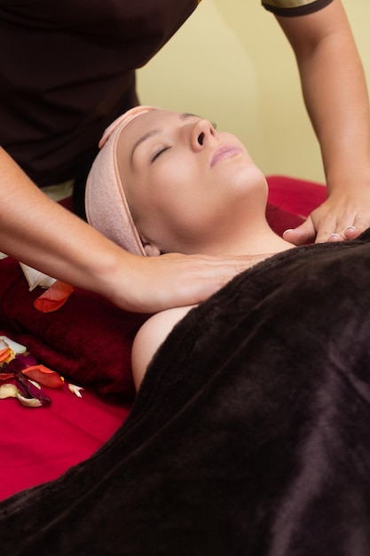 een masseuse in een cosmetische salon doet een Thaise massage op het gezicht van een jong meisje