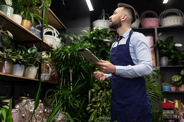 Een medewerker van een bloemenwinkel inventariseert met een tablet in zijn handen