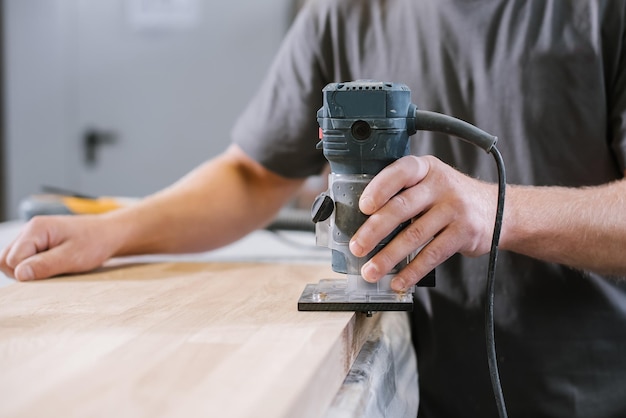 Een medewerker van een meubelfabriek schuurt een houten oppervlak met een schuurmachine