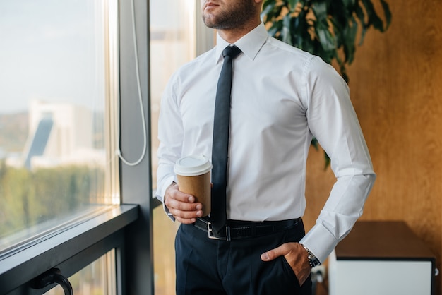 Een medewerker van het kantoor staat bij het raam. Financiën