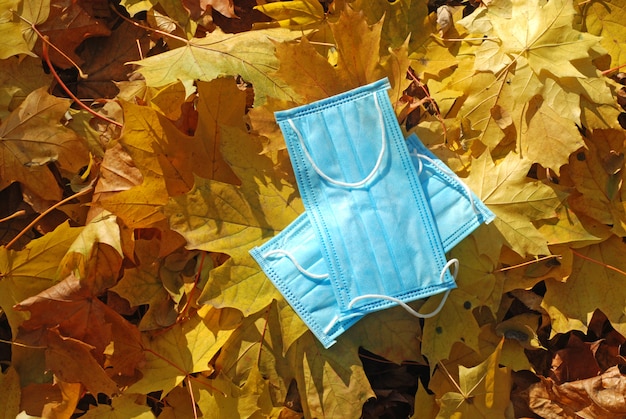 Een medisch masker voor bescherming tegen virussen ligt op gele, gevallen bladeren
