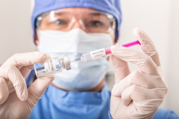 Een medisch werker die SARS-CoV-2-vaccin tegen het coronavirus in een injectie stopt.