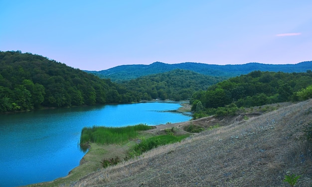 Een meer in de bergen met een blauwe lucht en bomen