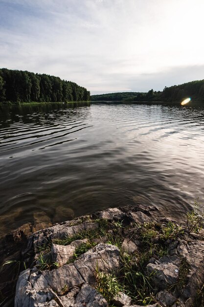 Een meer met een rotsachtige kust en bomen op de achtergrond