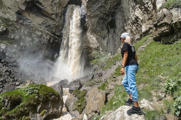 Een meisje bij de Sultansu-waterval, omringd door het Kaukasusgebergte in de buurt van Elbrus Jilysu, Rusland