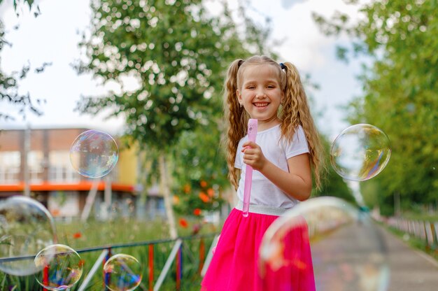 Een meisje blaast in de zomer zeepbellen in het park