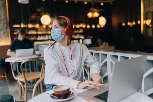 Een meisje dat in een coffeeshop zit met een uitbraak van het coronavirus