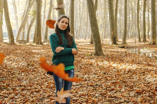 Een meisje dat in het herfstbos staat