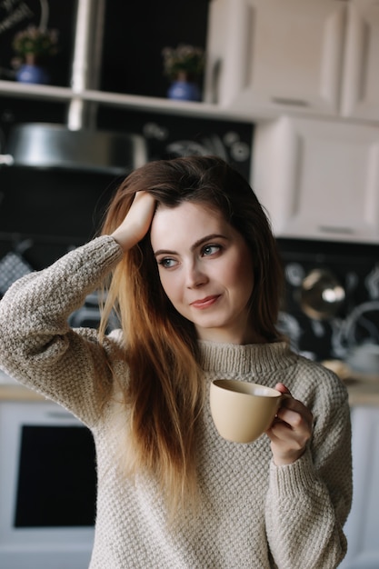 een meisje dat 's ochtends thuis koffie drinkt in de keuken