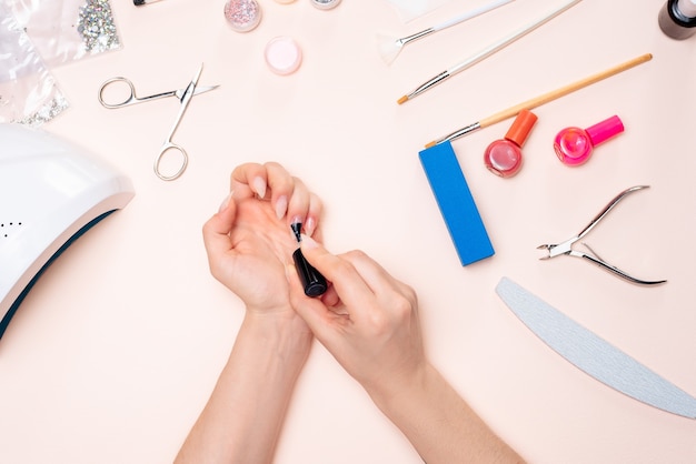 Een meisje doet een manicure thuis, handen close-up. het uitzicht vanaf de top