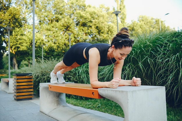 Een meisje doet een plankoefening op een bankje in het park