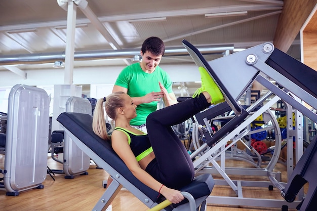 Een meisje doet oefeningen op de voetsimulator met personal trainer