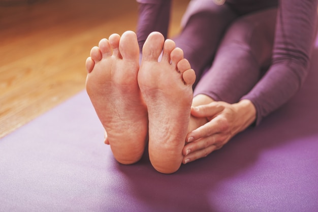 Een meisje doet yoga-asana's op een lila kleed in de woonkamer.