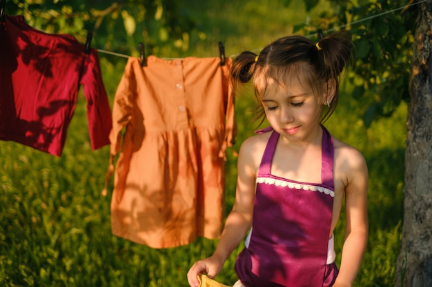 Een meisje draagt natte kleren na het wassen om aan een waslijn te drogen