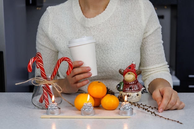 Een meisje Drie mandarijnen eetstokjes een kerstbeeldje en snoep op een witte tafel tegen een donkere keukenachtergrond