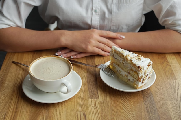 Een meisje drinkt koffie en eet een zoete cake in een café vrouwelijke handen close-up