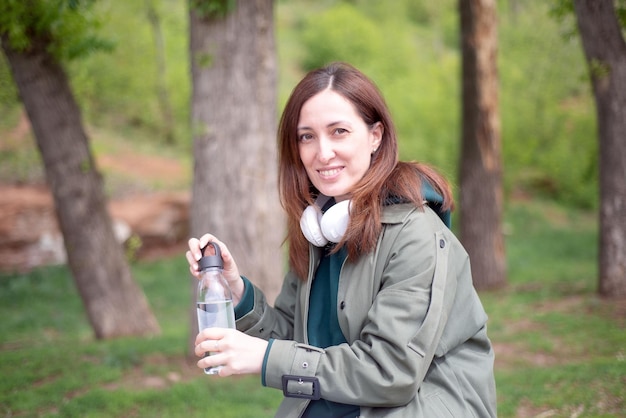 Een meisje drinkt water uit een fles water, zittend op een bankje in het park