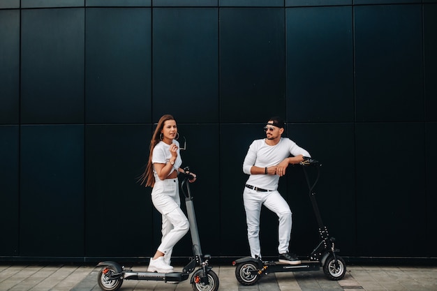 Een meisje en een jongen lopen op elektrische scooters door de stad, een verliefd stel op scooters.