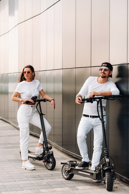 Een meisje en een jongen lopen op elektrische scooters door de stad, een verliefd stel op scooters.