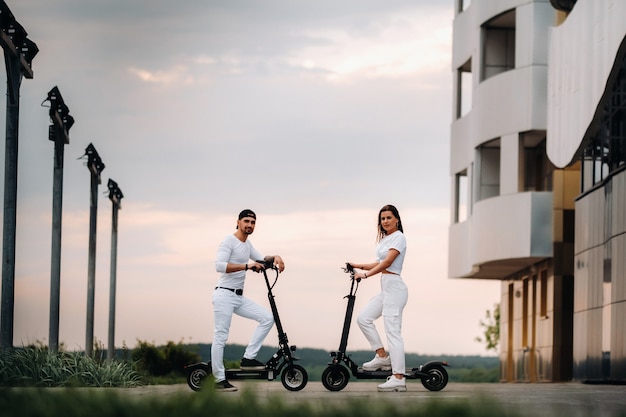 Een meisje en een jongen lopen op elektrische scooters door de stad, een verliefd stel op scooters.