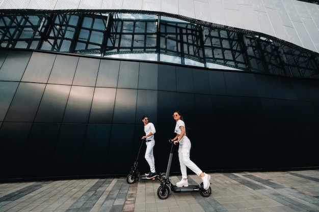 Een meisje en een jongen lopen op elektrische scooters door de stad, een verliefd stel op scooters.