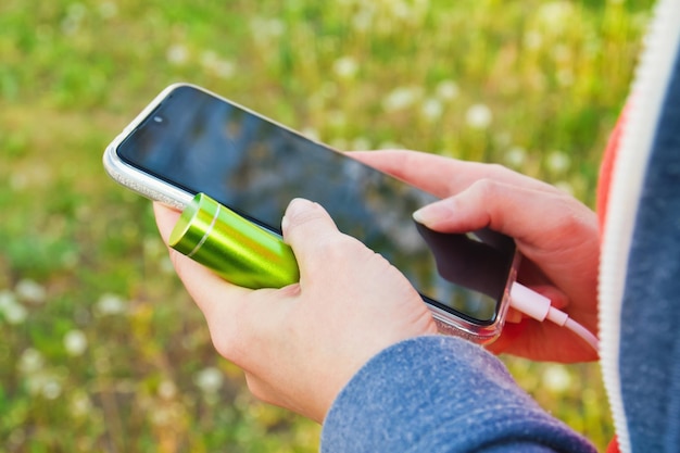 Een meisje gebruikt buitenshuis een smartphone tijdens het opladen van een externe powerbank