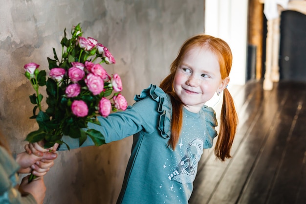 Een meisje geeft een boeket rozen aan haar moeder of zus, vreugde, jeugd, glimlach,