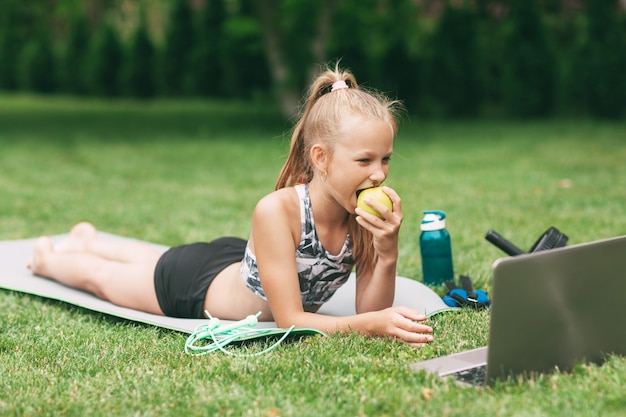 Een meisje houdt een appel in haar hand na een online buitentraining