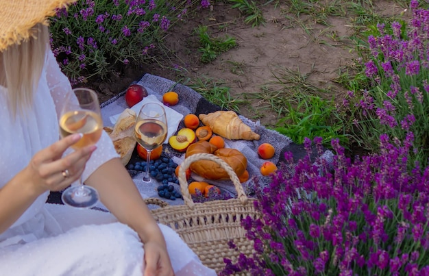 Een meisje houdt een glas witte wijn vast tegen de achtergrond van een lavendelveld Een meisje drinkt wijn in een lavendelveld