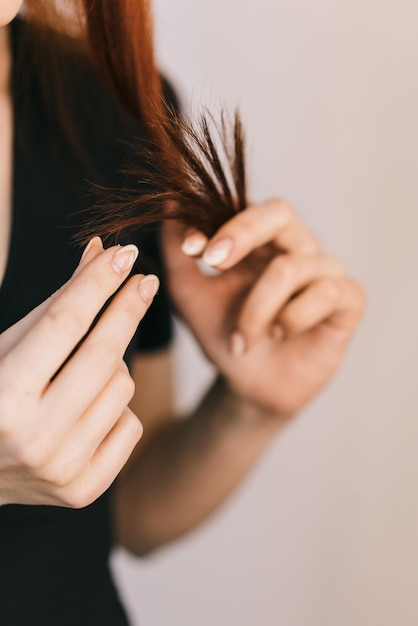 Een meisje houdt een haarlok in haar hand en inspecteert ze Close-up