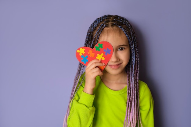 Een meisje houdt een hart vast met puzzelstukjes is het symbool van autisme