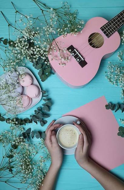 Een meisje houdt een kop koffie en een roze gitaar vast.