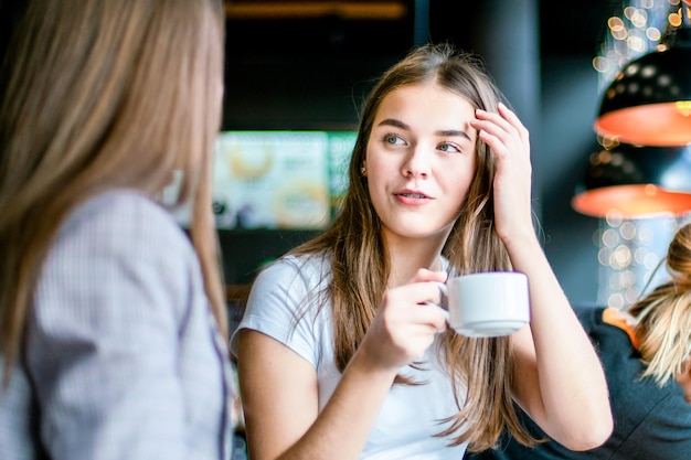 Een meisje houdt een kopje vast en maakt haar met haar hand recht