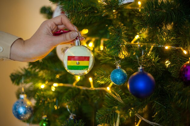 Een meisje houdt een versiering op een kerstboom met de vlag van bolivia