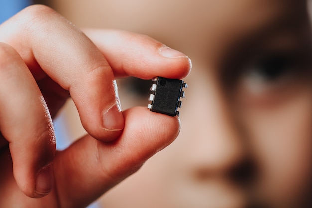 Een meisje houdt in haar hand en onderzoekt een kleine zwarte chip