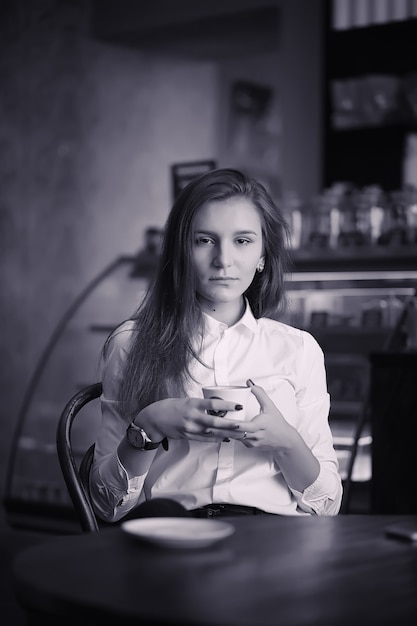 Een meisje in café drinkt koffie. Een vrouw zit te ontbijten in een restaurant. 'S Ochtends koffie in het koffiehuis voor het meisje.