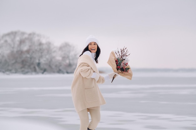 Een meisje in een beige vest en winterbloemen wandelt in de natuur in het sneeuwseizoen Winterweer