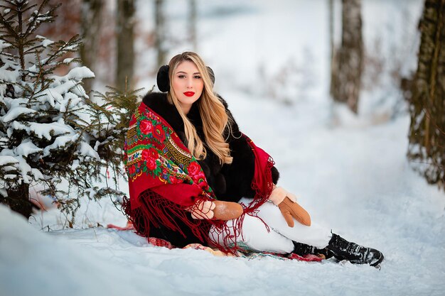 Een meisje in een besneeuwd bos in de winter Oekraïense folk rode sjaal Veel groene kerstbomen