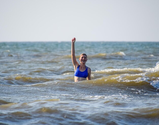 Een meisje in een blauw badpak baadt in de zee Vakantie aan zee