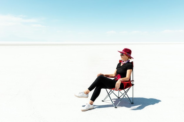 Een meisje in een cape zit op een opklapbare stoel en rust Salar de Uyuni Bolivia