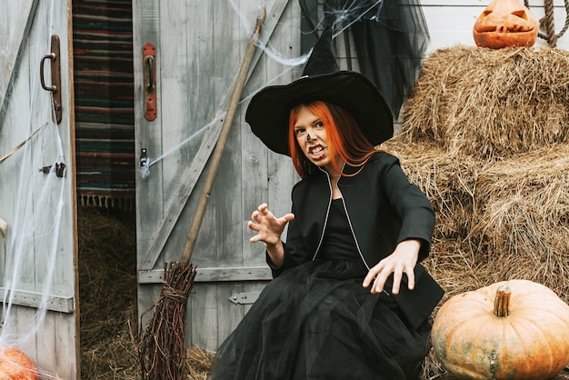 Een meisje in een heksenkostuum die plezier heeft op een Halloweenfeest op de versierde veranda