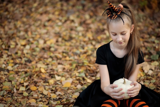 een meisje in een heksenkostuum voor Halloween meisje met pompoenen