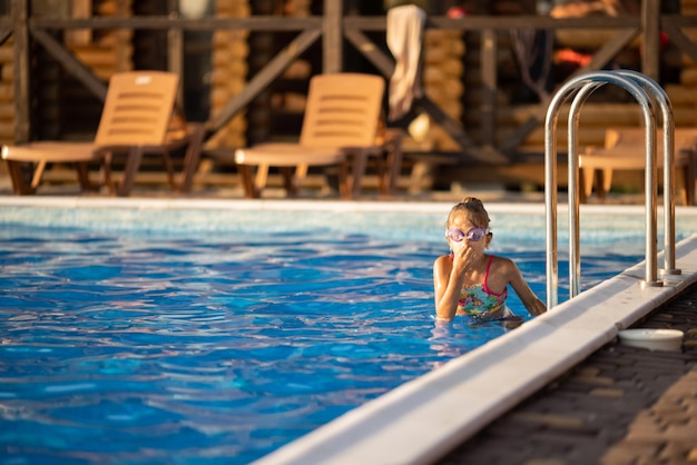 Een meisje in een helder zwempak met zwembril duikt in een zwembad met helder transparant water