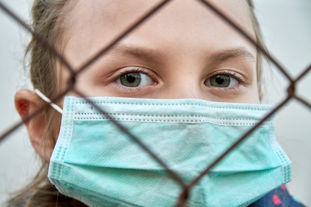 Een meisje in een medisch masker. quarantaine. een meisje in de quarantainestreek. coronavirus concept. meisje dat beschermend masker draagt.