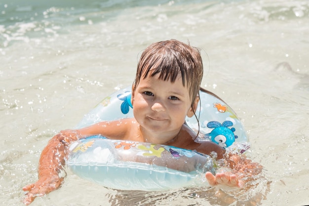 Een meisje in een opblaasbare cirkel om te zwemmen op vakantie in het zwembad, de zee. Spa concept, zwemlessen, vakanties, waterbehandelingen