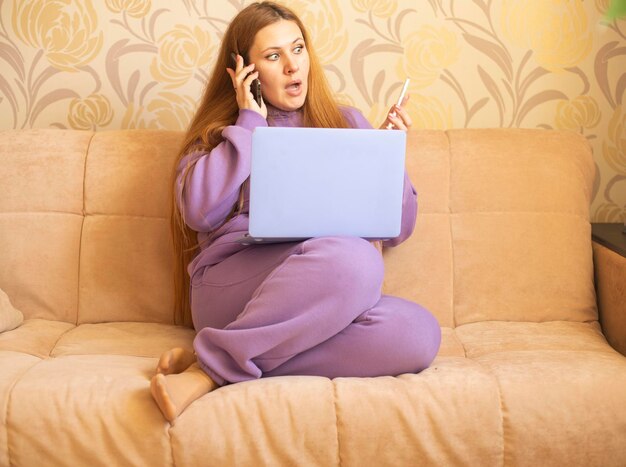 Foto een meisje in een paars pak met een laptop op de bankcommunicatie op sociale media