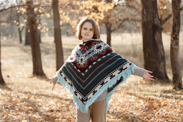 Een meisje in een poncho een wandeling in het herfstbos