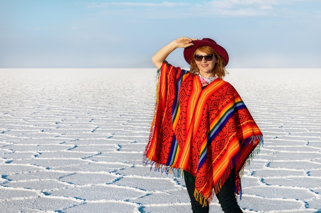 Een meisje in een poncho en een hoed tegen de achtergrond van Salar de Uyuni Bolivia