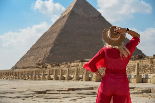 Foto een meisje in een rode jurk kijkt naar een egyptische piramide